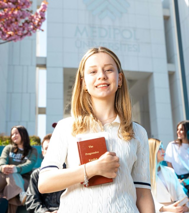 Happy university students socializing on campus, with a focus on a smiling young woman holding a book.